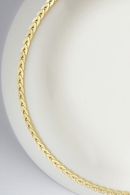 "Elysian halskjede i slitesterkt stål med gylden finish, 38 cm langt, med 5 cm forlengelse."