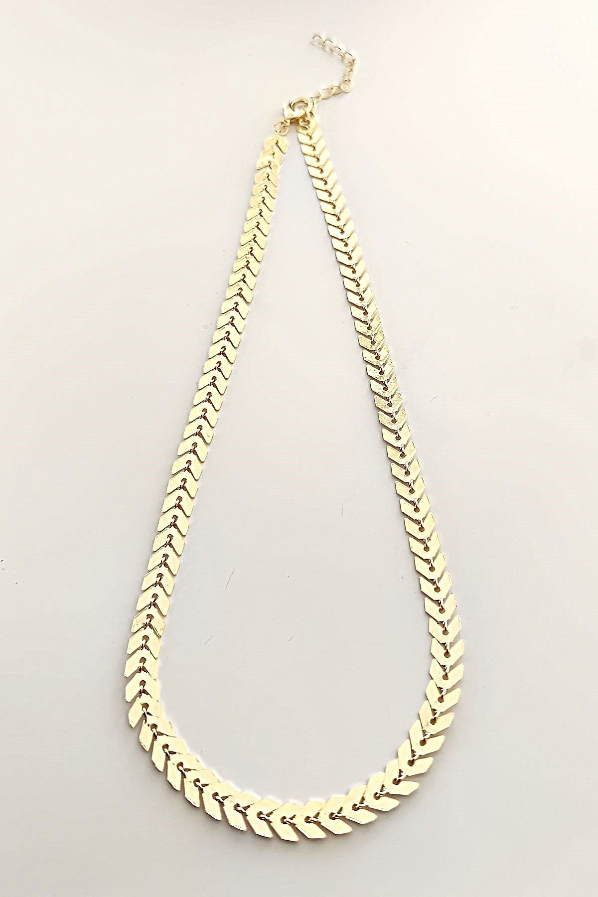 "Elysian halskjede i slitesterkt stål med gylden finish, 38 cm langt, med 5 cm forlengelse."